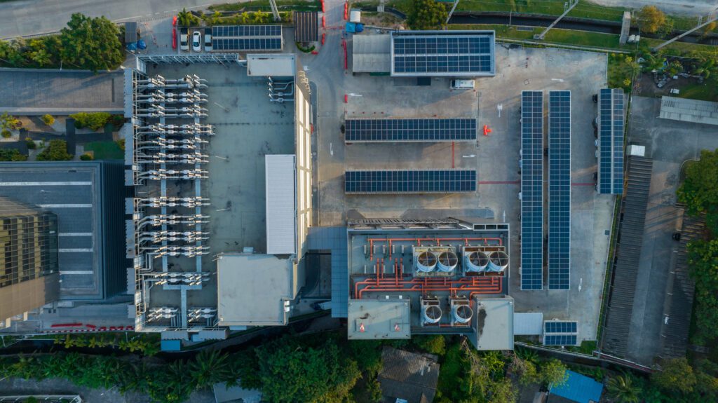 Top view of blue solar photo voltaic panels system on high apartment building roof top on sunny day. Renewable ecological green energy production concept.